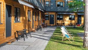 Ein holzgestütztes Häuschen mit einer überdachten Terrasse, Sitzgelegenheiten im Freien und einem Rasen.