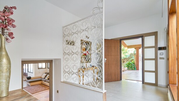Un interior modern amb una escala, un panell blanc decoratiu i vista a zona exterior.