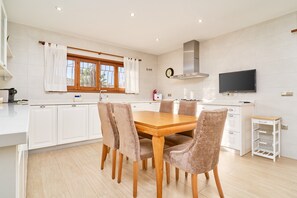 A modern kitchen with white cabinets, a wooden dining table, and four chairs. - Villa Dopimar with Private Pool, Wi-Fi, and Air Conditioning (Rincón de la Victoria)