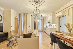 Ein modernes Wohnzimmer mit einer Couch, einem Esstisch für vier Personen und einer Küche im Hintergrund.