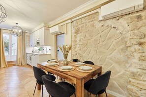 Ein Essbereich mit einem Holztisch, gedeckt für vier Personen, schwarzen Stühlen und einer Steinsäule.
