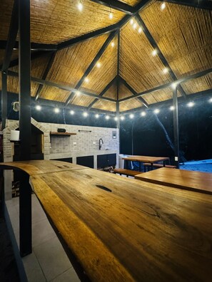 Una estructura de madera al aire libre con un muro de ladrillo, un lavamanos y una zona de parrillada.