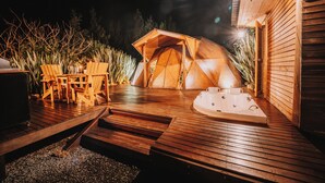 A wooden deck with a hot tub, wooden chairs, and a tent-like structure. - Ráquira Glamping (Ráquira)