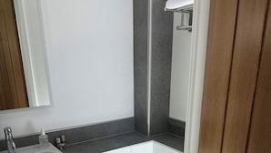 A modern bathroom with a white sink, mirror, and toilet.