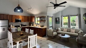 A spacious kitchen with a dining area, a living room with a sofa, and a ceiling fan. - Private 2 Bedroom Home | Pool | Near Beach (Coco)