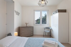 Una camera da letto con un letto, una cassettiera, una sedia e una finestra vista.