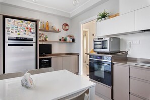 Una cucina moderna con elettrodomestici in acciaio inossidabile, un piano di lavoro bianco e un'area pranzo.