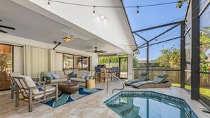 A spacious outdoor living area with a pool, seating, and a ceiling fan. - Chardonnay Beach Escape, Naples, Florida (Naples)