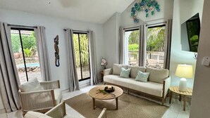 A living room with a ceiling fan, a sofa, a coffee table, and a TV. - Family 2BR Home | Pool | BBQ Rancho | Near Beach (Coco)