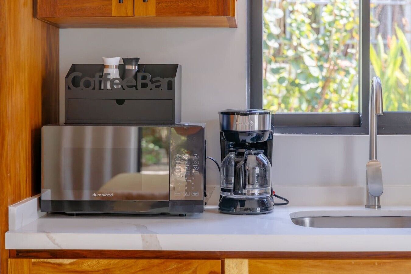 A kitchen with a coffee maker, a microwave, and a coffee machine on the counter.