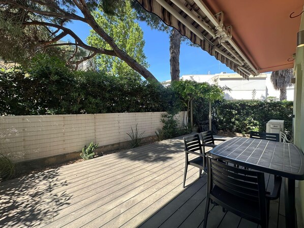 Eine Terrasse mit Tisch und Stühlen, umgeben von einer Holzdielenveranda und einem weißen Zaun.