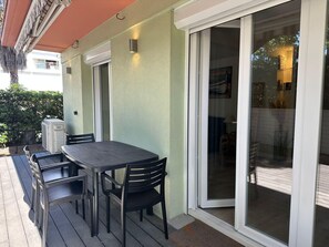 Eine Terrasse mit Tisch und Stühlen, eine Glasschiebetür und ein Klimagerät.