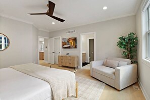 Une chambre à coucher comprenant un lit, un canapé, un ventilateur de plafond, une commode et une plante.