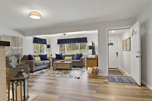 A spacious living room with a grey sofa, blue cushions, a coffee table, and a television. - Lake Como private home. Sleeps 6 (Lake Geneva)