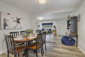 Ein Essbereich mit Holztisch und -stühlen, einer Kühlpflanze und einem Bild an der Wand.