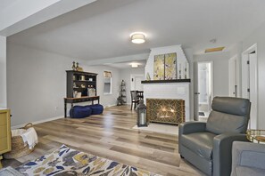 Ein geräumiges Wohnzimmer mit Kamin, einer dunkelbraunen Ledersofa und Holzboden.