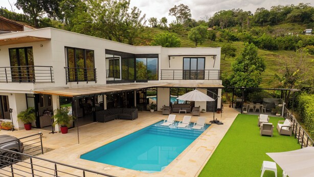 A modern two-story house with a swimming pool, outdoor seating, and a lush green lawn. - Modern country house in Sopetran, Antioquia. (Antioquia)