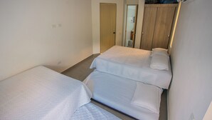 A compact room with two single beds, a wooden wardrobe, and a small bathroom visible through a door. - Modern country house in Sopetran, Antioquia. (Antioquia)