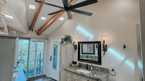 Une cuisine spacieuse dotée d’un grand îlot central, d’un ventilateur de plafond et de fenêtres de toit.