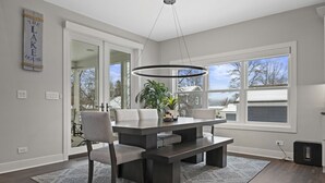 A modern dining room with a large table, benches, and chairs. There is a hanging light fixture above the table. - New Luxe Lake Home - Entertainment Rms - Lake view (Lake Geneva)