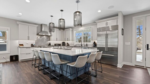 A modern kitchen with a large island, bar stools, stainless steel appliances, and pendant lighting. - New Luxe Lake Home - Entertainment Rms - Lake view (Lake Geneva)