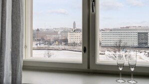 A window with a view of a cityscape, including buildings and a parking lot. - Premium 7th Floor Apartment - Sea View & Historic District (Helsinki)