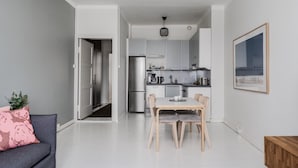 A modern kitchen with white cabinets, a stainless steel refrigerator, and a dining area with a wooden table and chairs. - Premium 7th Floor Apartment - Sea View & Historic District (Helsinki)