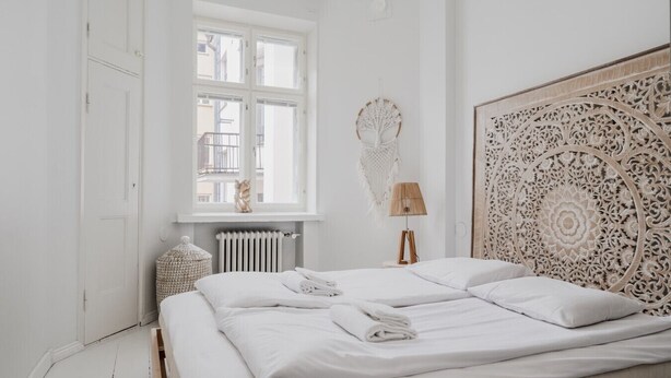 A minimalist bedroom with a large bed, a window with a view, and a decorative headboard. - Premium 7th Floor Apartment - Sea View & Historic District (Helsinki)