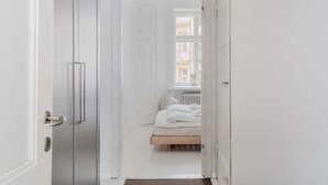 A narrow hallway with a brown rug leading to a bedroom with a bed and a window. - Premium 7th Floor Apartment - Sea View & Historic District (Helsinki)