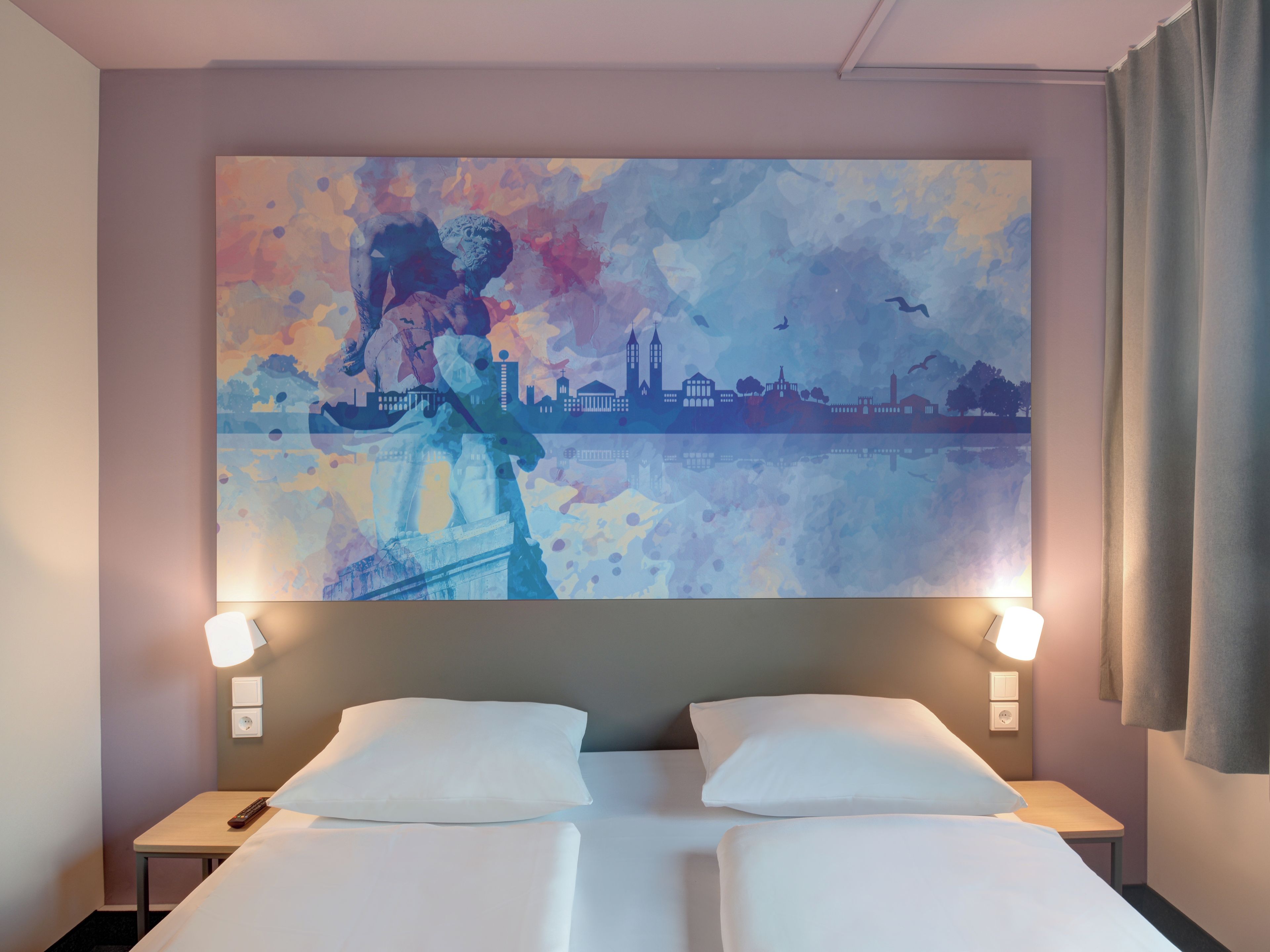 Una camera d'albergo con un letto, due comodini e un grande quadro astratto appeso al muro.