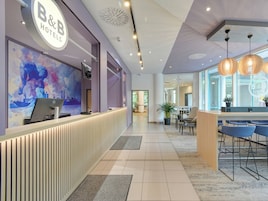 Zona de recepción de un hotel con diseño moderno, que incluye un mostrador de recepción, un ventanal grande y un área de descanso con sillones.