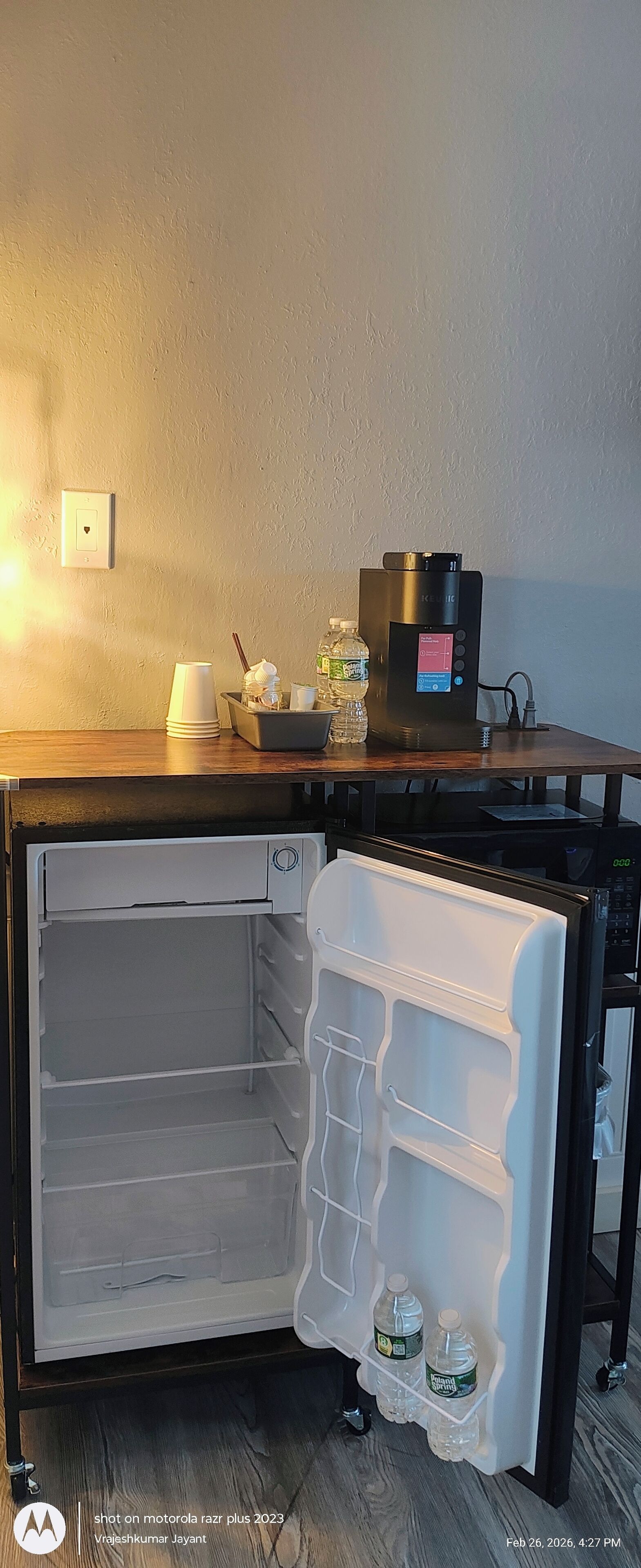 Un frigorifero compatto dotato di display digitale, erogatore d'acqua e una piccola macchina per il caffè sopra.
