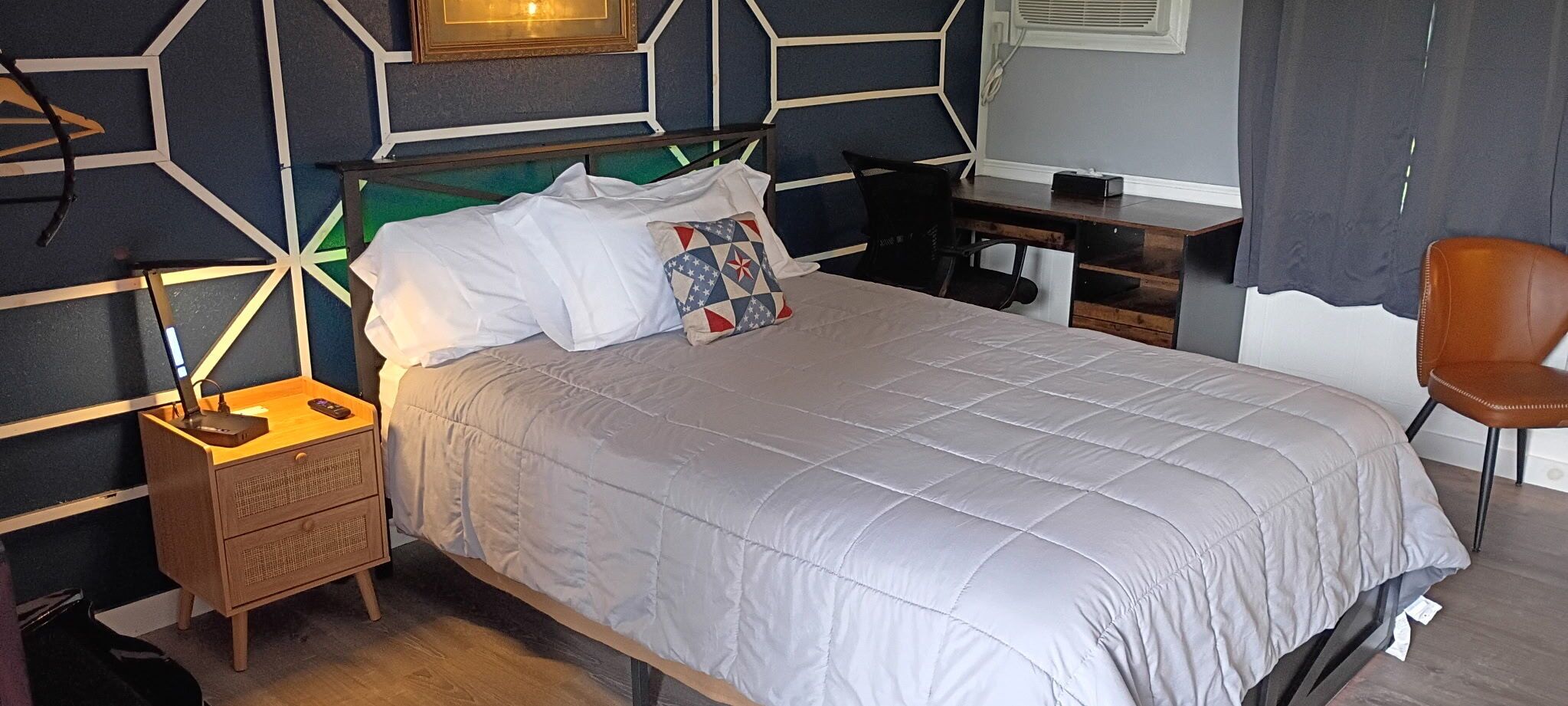 A neatly arranged bedroom with a bed, bedside table, lamp, and a chair.