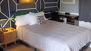 A neatly arranged bedroom with a bed, bedside table, lamp, and a chair.