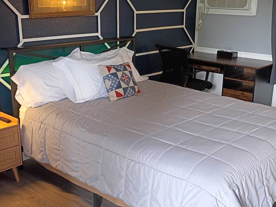 A neatly arranged bedroom with a bed, bedside table, lamp, and a chair.