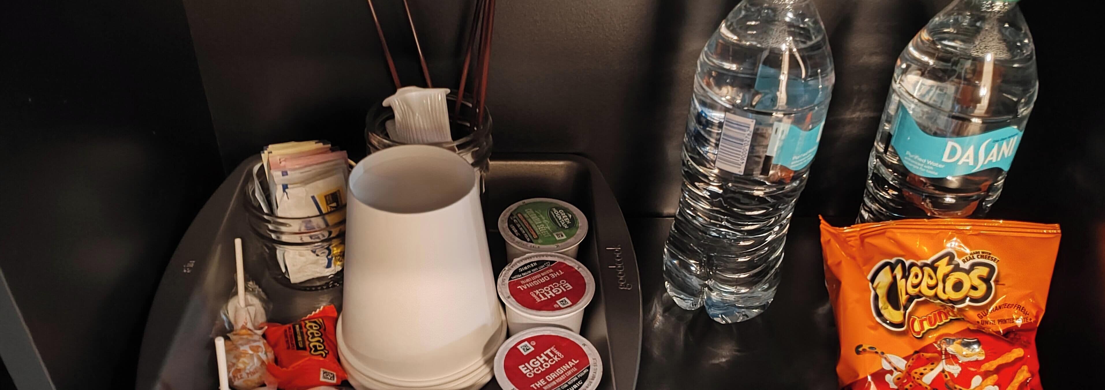 A tray with snacks, bottled water, and a white mug.