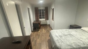 Ein Schlafzimmer mit einem Bett, einem Schreibtisch, einem Stuhl und einem Fenster.