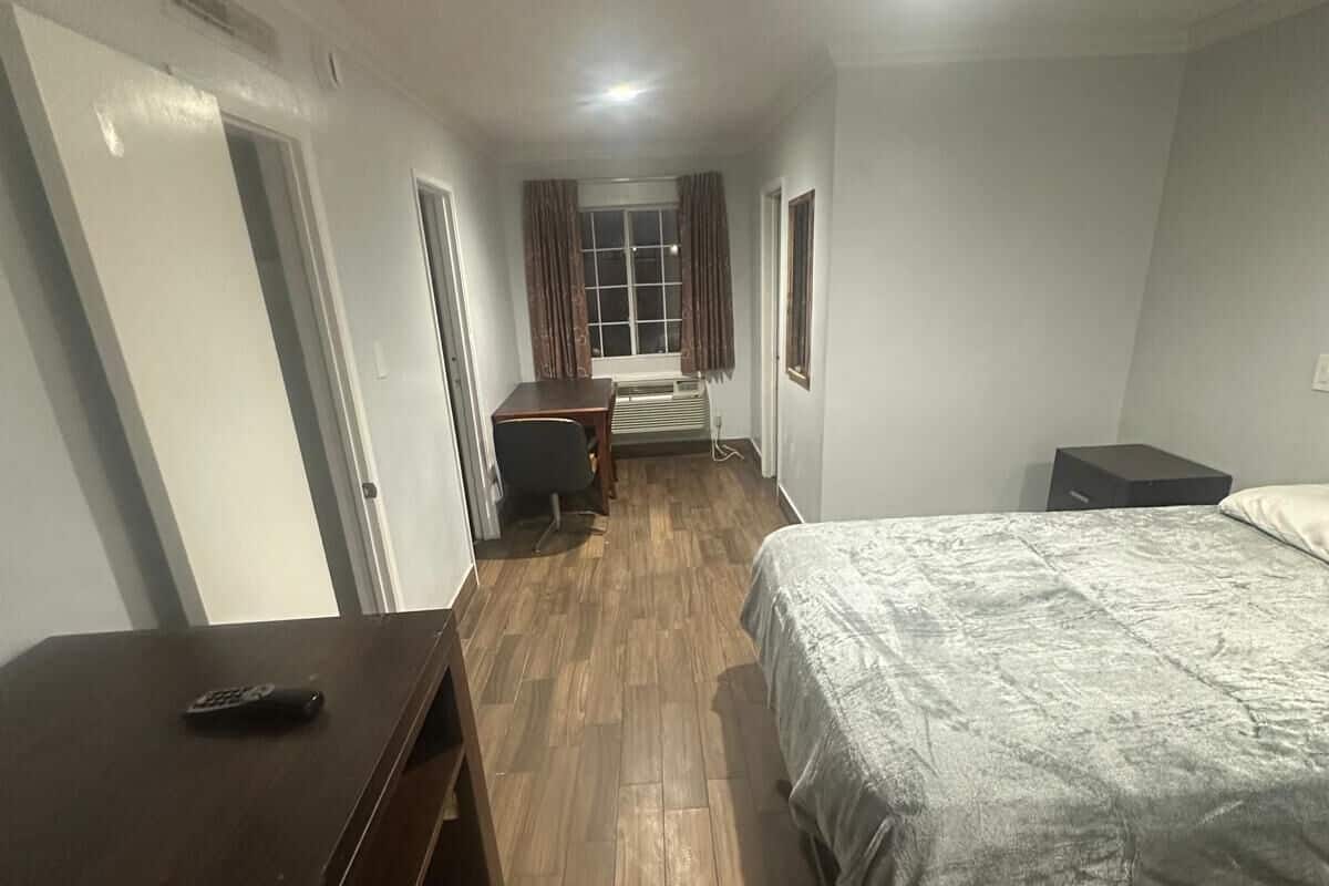 Un dormitorio con cama, escritorio, silla y ventana.