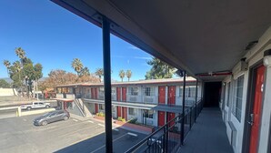 Ein Motel mit überdachtem Gang, Parkplatz und Blick auf Palmen.