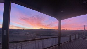 En träveranda med ett räcke som vetter ut mot ett ökenlandskap i solnedgången.
