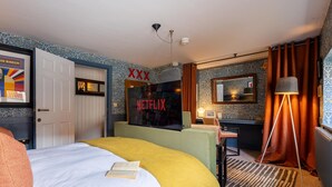 Ein Hotelzimmer mit einem Bett, einem Schreibtisch, einem Spiegel, einer Lampe und einer Wand mit einem Netflix-Logo.