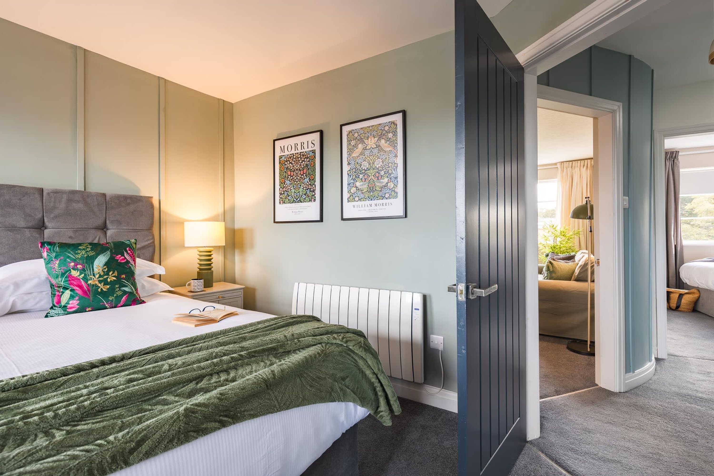 A neatly arranged bedroom with a bed, bedside lamp, and two framed artworks on the wall.