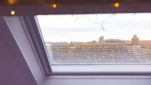 Vista a través d'un finestral de sostre amb una paret de pedra i una xemeneu.