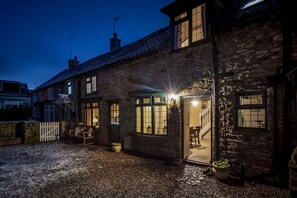 A stone house with a gravel driveway, a wooden fence, and a bench. - Garth Cottage West Ayton Scarborough (Scarborough)