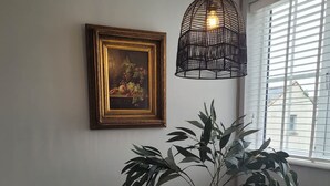 Uma área de refeições com uma mesa redonda, cadeiras, um vaso de planta, um quadro emoldurado e um pendente.