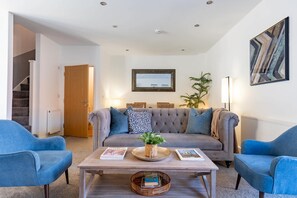 A modern living room with a grey sofa, two blue armchairs, a wooden coffee table, and a framed picture on the wall. - Welton View Coastal Getaway in Whitby (Whitby)