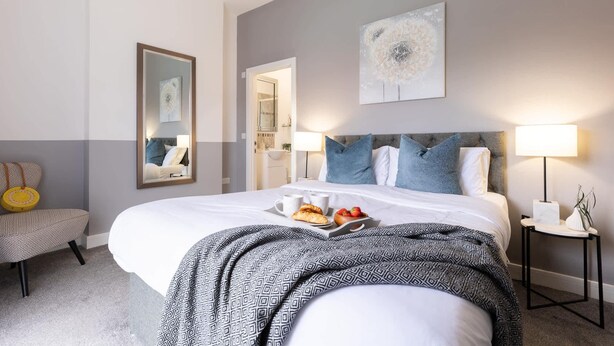 Quarto de hotel com cama grande, abajures, espelho e bandeja com itens de café da manhã.