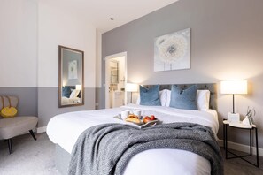 Une chambre d’hôtel avec un grand lit, des lampes de chevet, un miroir et un plateau contenant des articles pour le petit-déjeuner.