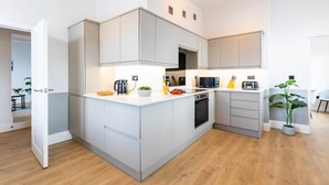 A modern kitchen with white cabinetry, a central island, and a microwave. - Ocean Pearl - Seaside Sanctuary (Scarborough)