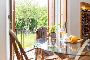 Un coin repas avec une table en verre, des chaises, une plante en pot et un meuble à bouteilles.